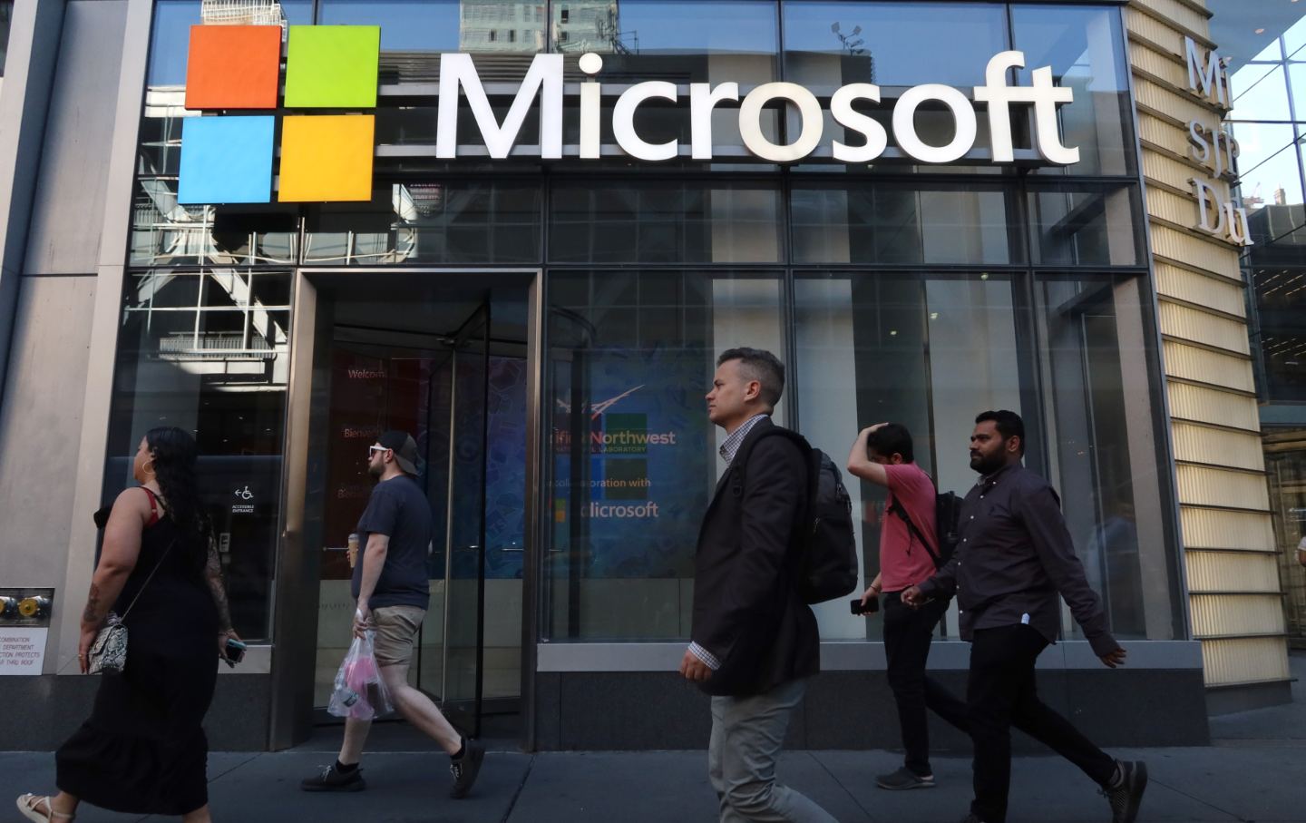 People walk past the front entrance to a Microsoft office building on 8th Avenue in New York City on June 24, 2025.